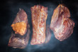 Pork meat hanging on hooks in smoke. Preparing smoked ham.