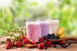 Fresh milk, strawberry, blueberry and banana drinks on wooden table, assorted protein cocktails with fresh fruits.