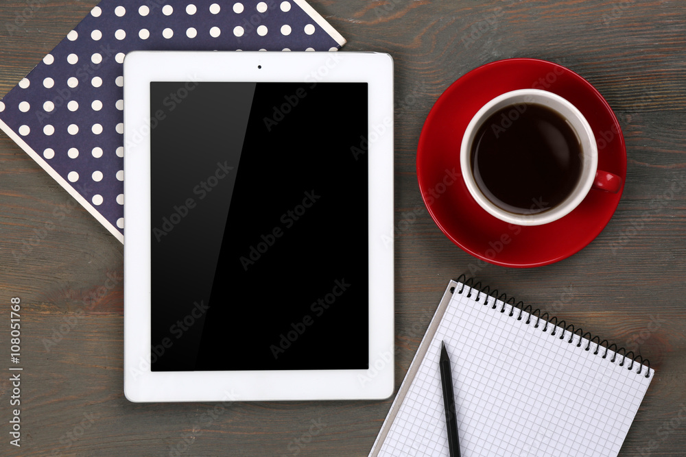 Digital tablet with cup of coffee and notebook on wooden table, closeup