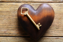 Golden Key With Brown Heart On Wooden Background