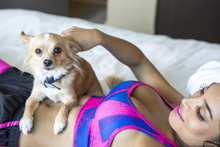 Hispanic Athlete Petting Dog On Bed