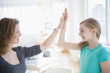© JGI/Jamie Grill/Blend Images - Caucasian mother and daughter high fiving in living room