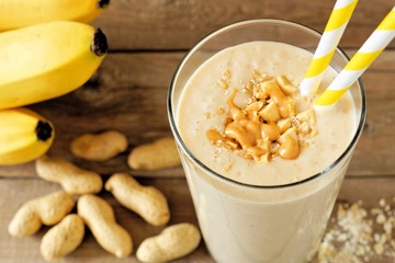 Wall Mural - Peanut butter banana oat smoothie with paper straws on rustic table with scattered ingredients