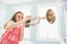 Caucasian Girl Playing Trumpet In Bedroom
