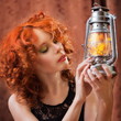 Beautiful red-haired girl with a kerosene lamp.