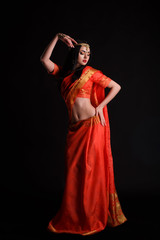 Wall Mural - Full body traditional Indian girl in red sari costume standing isolated on black background. 