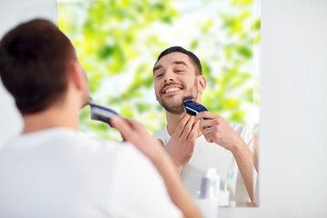 Canvas Print - man shaving beard with trimmer at bathroom