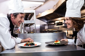 Two smiling chefs leaning on counter with meal plates