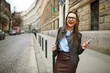 © vladstar - Businesswoman walking down the street while using the smart phon