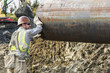 © Don Mason/Blend Images - Worker hauling pipe at construction site