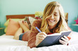 © Peathegee Inc/Blend Images - Caucasian woman writing in diary on bed