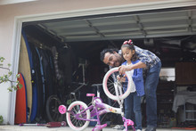 Hispanic Father Teaching Daughter To Repair Bicycle