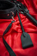 Riding crop, a whip flogger, leather choker and leash on red satin, kinky sex toys for dom / sub sexual and other forms of kink