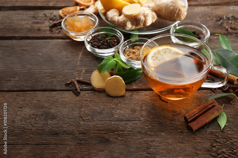 Cup of tea with ginger and cinnamon on wooden background