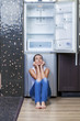 Unhappy and hungry girl near empty fridge