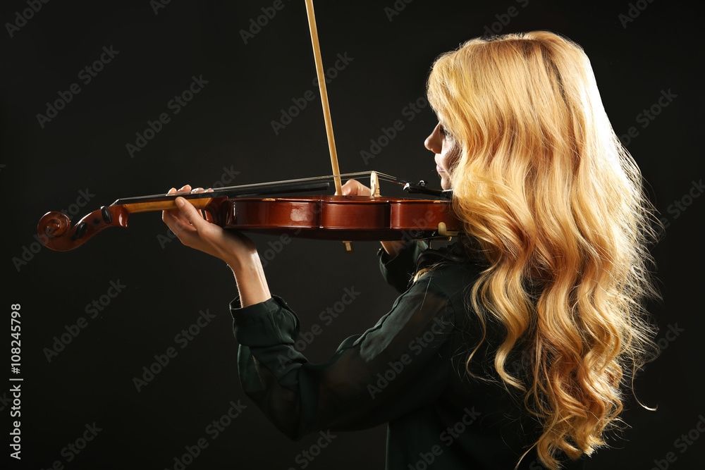 Musician plays violin on black background, close up