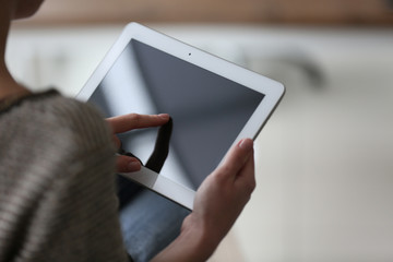 Wall Mural - Young woman using tablet on blurred background