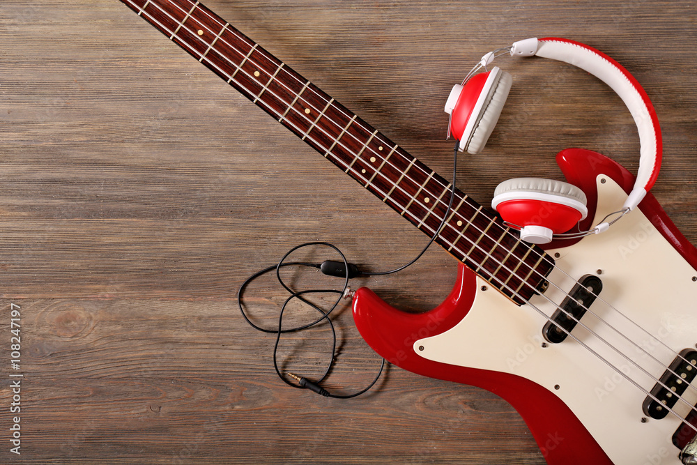 Electric guitar with headphones on wooden background