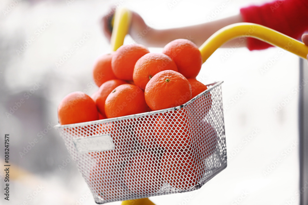 Woman driving a bicycle with tangerines in basket