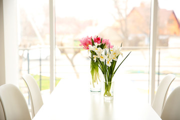 Wall Mural - Beautiful tulips and irises on dinning table on window background