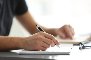 Canvas Print - Student's hand writing in exercise book at the table