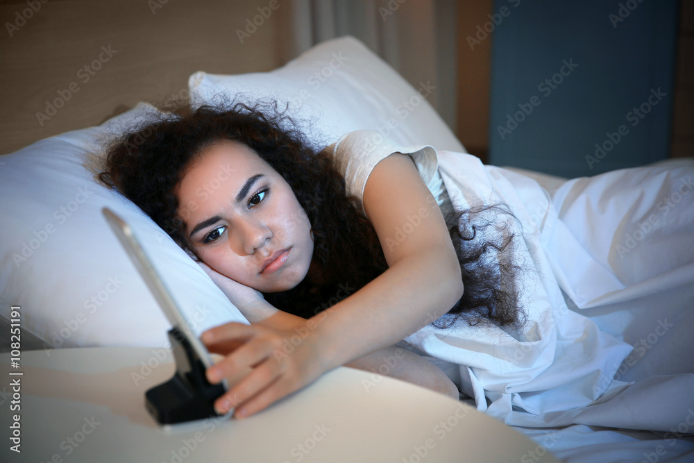 Beautiful girl in bed and mobile alarm clock