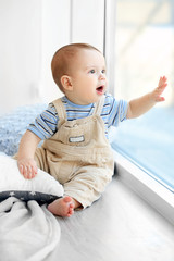 little baby boy looking out the window at home