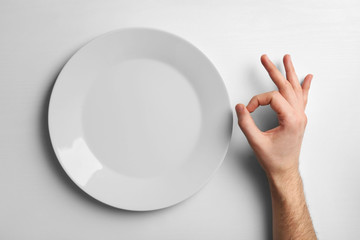 Canvas Print - Plate and male hand showing OK sign, isolated on white