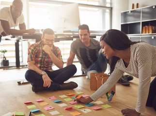 Canvas Print - Group of workers sitting around notes on floor