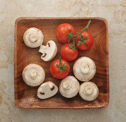 Wall Mural - raw whole mushrooms in a wooden bowl with tomato