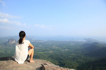 young asian woman enjoy the view at mountain peak cliff