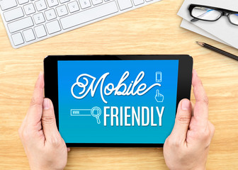 Poster - Hand holding tablet with Mobile friendly word on wood table ,Dig