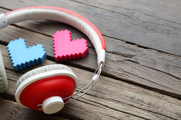 Wall Mural - Red headphones near hearts on wooden background