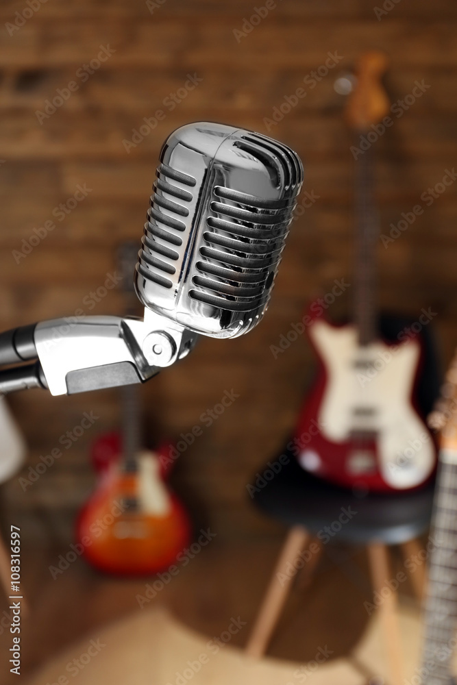 Microphone in front of electric guitars on wooden background