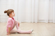 © Africa Studio - Little cute girl in pink leotard sitting on floor at dance studio