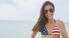 Happy American Woman Celebrating Doing Thumbs Up With USA Flag Style Bikini On Beach. Excited Cheering Sexy Girl Portrait Smiling At Camera Joyful.