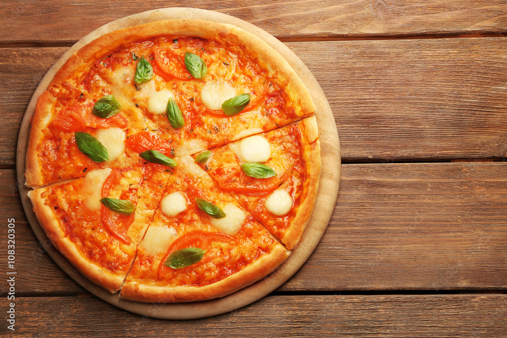 Sliced Margherita pizza on wooden background