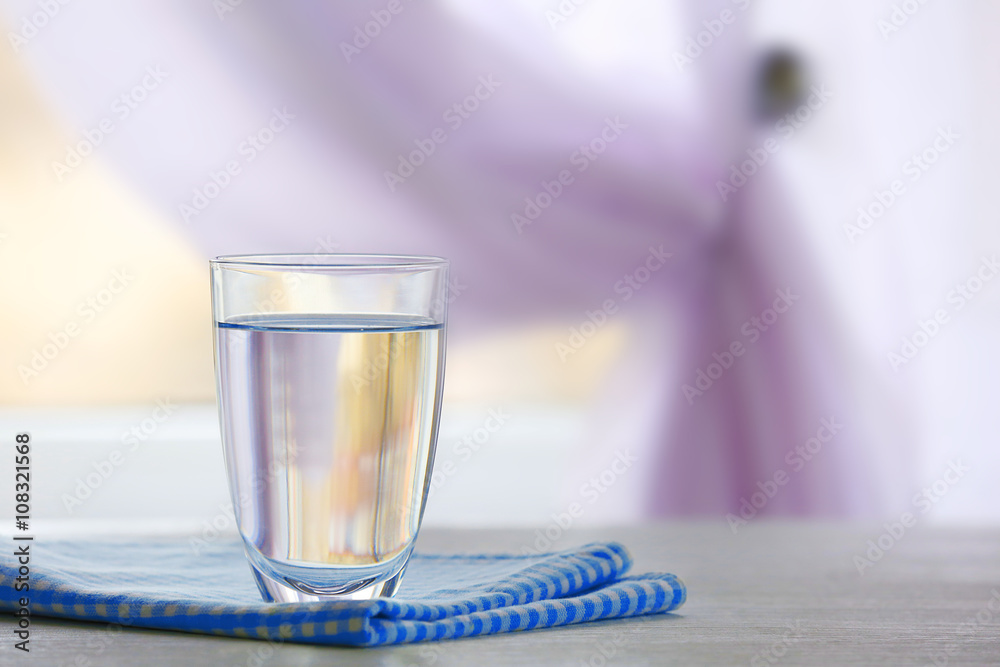 Glass of water with napkin  on light background