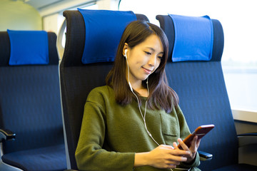 Wall Mural - Woman sitting in train compartment and listening to music