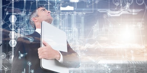Poster - Composite image of businessman in suit holding his laptop
