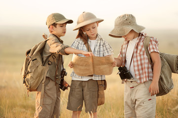 group of kids travelers read a map at sunset