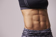 © Guerilla - Mid-section crop shot of muscular young woman’s abs