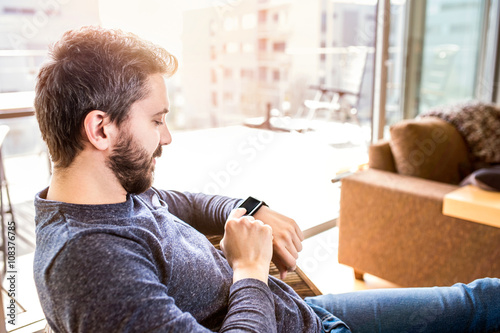 Fotografía Man working from home using smart watch, living room