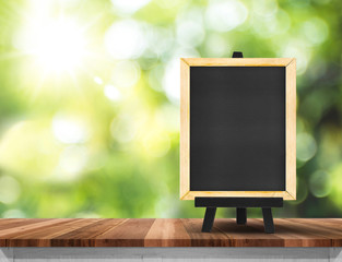 Aufkleber - Blank blackboard on wood table top with sun and blur green tree