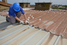 Construction Worker Inspects Old Metal Roof