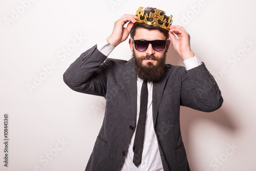 Fotografie, Obraz Portrait handsome young cheerful man in suit with crown looking at camera with s