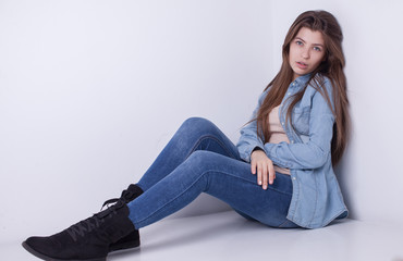 Young European attractive sexy fashion model with long blond natural hair, beautiful eyes, full lips, perfect skin is posing in jeans and shirt in studio for glamour vogue test photo shoot