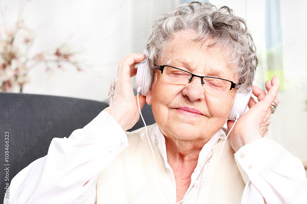 Chwila relaksu, babcia odpoczywa słuchając muzyki. Starsza kobieta z słuchawkami na uszach słucha muzyki - obrazy, fototapety, plakaty 