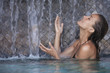 belle femme dans une piscine sous des chutes d'eau