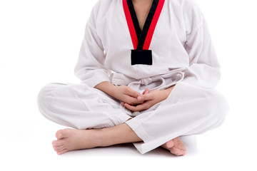 Young boy in taekwondo uniform doing meditation isolated on whit